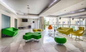 a modern living room with green and orange chairs , a television , and a balcony overlooking the water at Holiday Inn Sittingbourne