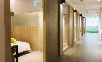a modern , minimalist room with wooden walls and doors , featuring a bed with yellow pillows at Hub Hotel