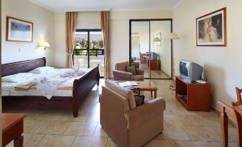 a spacious living room with a couch , chair , and tv is shown next to a bedroom with a bed at Panareti Coral Bay Resort