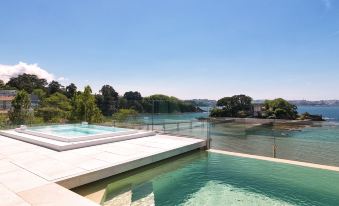 a modern house with a swimming pool and a glass walkway overlooking the water , creating a serene and picturesque scene at Noa Boutique Hotel