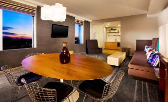 a dining table with chairs is set in a room with a couch , television , and coffee table at Aloft Mount Laurel