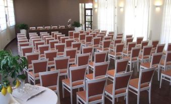 a conference room set up for a meeting , with chairs arranged in rows and a table in the center at Hotel Cavaliere