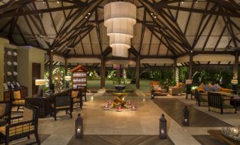 a large , open - air restaurant with wooden beams and multiple tables , each filled with food and drinks at Taj Exotica Resort & Spa