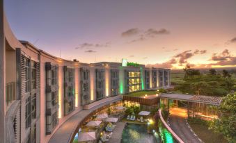 a large hotel with a pool and several lounge chairs is illuminated by lights at dusk at Holiday Inn Mauritius Mon Tresor