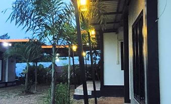 a house with a porch and palm trees , along with the beach in the background at Khun Naparn Resort