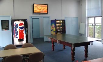 a ping pong table is set up in a room with chairs and vending machines at Lucas Heights Motel