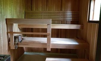 a wooden room with multiple benches , including a bunk bed and a chair , as well as a stove at Simola