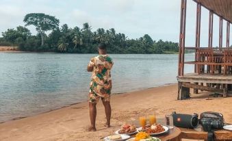 a man is standing on a sandy beach , enjoying a meal while holding a cell phone at Aqua Safari Resort