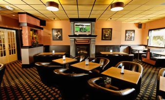 a room with multiple tables and chairs , a fireplace , and a television mounted on the wall at Best Western Cowichan Valley Inn