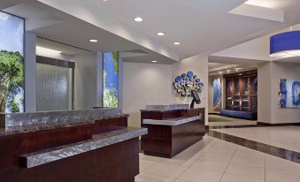 a modern hotel lobby with a marble reception desk , blue painting on the wall , and large windows at Hyatt Regency Dulles