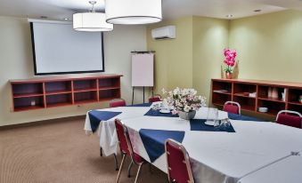 a conference room with a round table surrounded by chairs , and a whiteboard on the wall at Hotel le Versailles