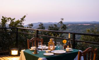 a table set with plates , glasses , and candles on a balcony overlooking a beautiful view at The Machan