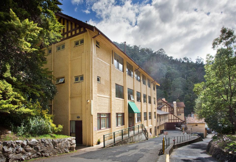 a large building with a green awning is situated on a street next to a body of water at Jenolan Caves House