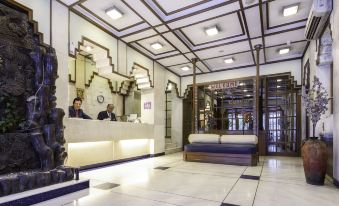 a modern hotel lobby with white marble floors , a reception desk , and a black sofa at Garden Hotel