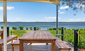 a wooden deck overlooking a body of water , with a table and chairs set up for outdoor dining at BreakFree Raffertys Beach Resort