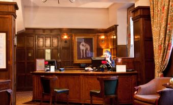 a hotel reception area with two people at the desk , one of them working on a computer at Billesley Manor Hotel & Spa, a Tribute Portfolio Hotel