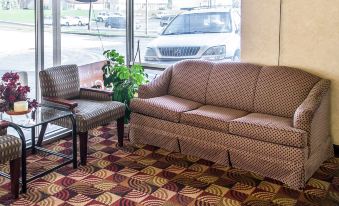 a brown couch and a chair are placed in front of a window with a car parked outside at Economy Inn & Suites