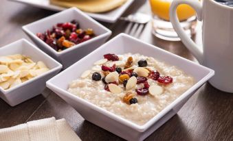 a dining table with a variety of bowls filled with different types of food , including oatmeal , nuts , and fruit at Hyatt House Minot