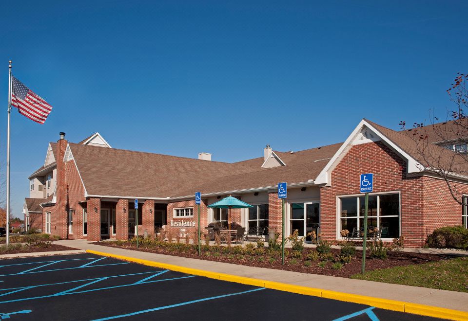 a large building with a parking lot in front of it , and a sign on the ground at Residence Inn Lansing West