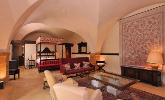 a luxurious hotel room with an ornate canopy bed , comfortable seating , and a large flat - screen tv at Chateau de Bagnols