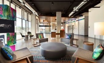 a modern , well - lit living room with a round coffee table in the center , surrounded by various seating options and comfortable seating at Aloft Hillsboro-Beaverton