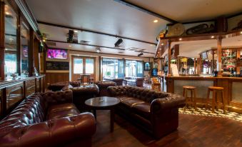 a cozy bar with several couches and chairs , as well as a tv mounted on the wall at Mick O'Sheas