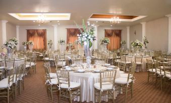 a large banquet hall with multiple round tables and chairs , all set for a wedding reception at Hotel Mediterraneo
