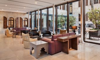 a modern living room with a large window , several couches , chairs , and tables , all set against a backdrop of glass walls at The Setai Tel Aviv, a Member of the Leading Hotels of the World