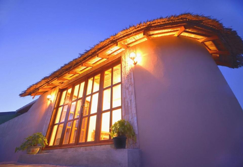 a white building with large windows and wooden beams , lit up by yellow lights against the night sky at Sunshine Lodge