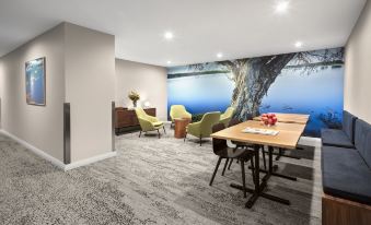 a modern conference room with a large mural on the wall , wooden tables , and green chairs at Quest Innaloo