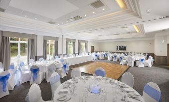 a large dining room with round tables covered in white tablecloths and chairs arranged for a formal event at Doubletree by Hilton Dartford Bridge