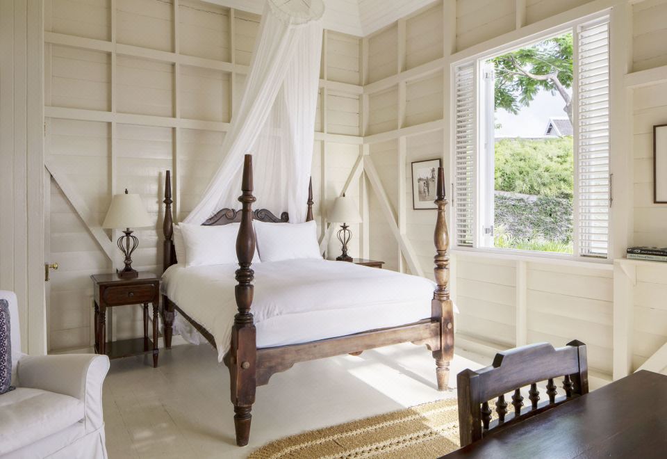 a white bedroom with a four - poster bed , a wooden dresser , and a window overlooking a beautiful view at Strawberry Hill