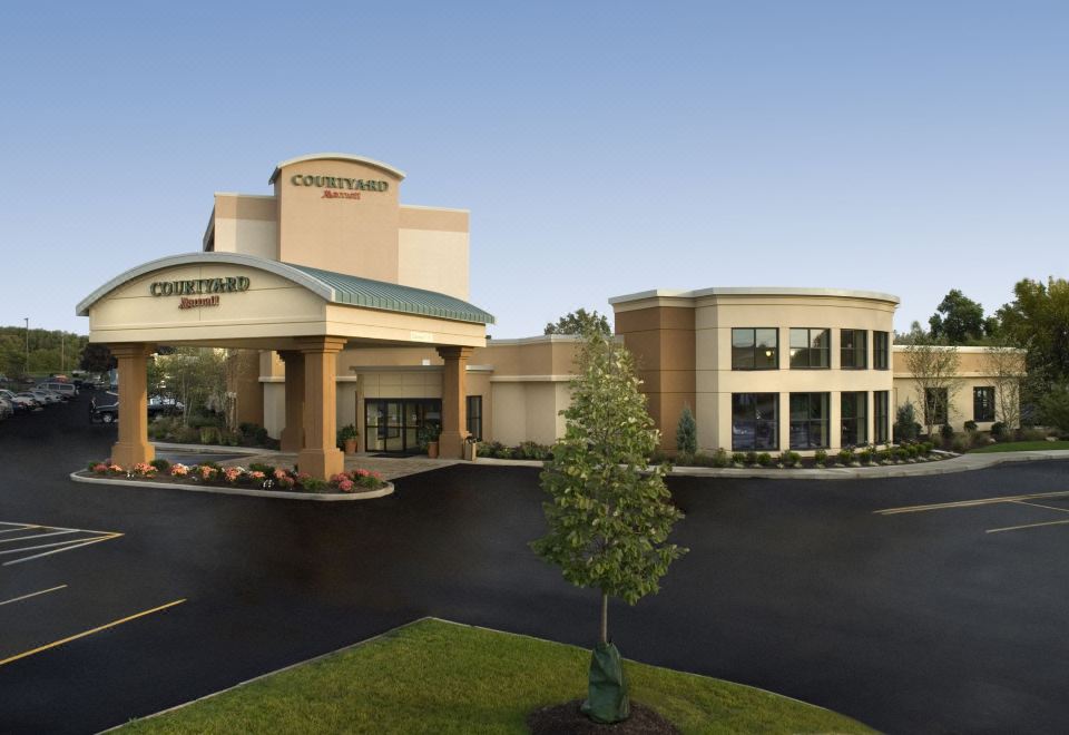 a large , modern hotel building with a green roof and a tree in front of it at Courtyard Canton