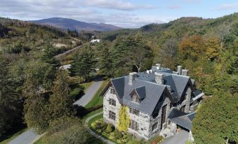 an aerial view of a large stone mansion surrounded by trees , with mountains in the background at Castle Hill Resort and Spa