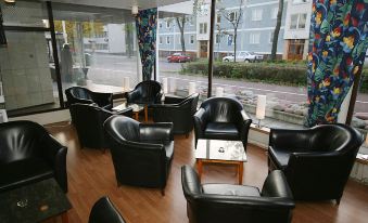 a room with several black leather chairs arranged in a circle around a coffee table at Hotel Savoy