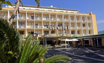 a large hotel building with multiple balconies , surrounded by palm trees and other greenery , under a clear blue sky at Grand Hotel Moon Valley