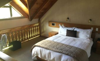 a large bed with a wooden headboard and footboard is situated in a room with a sloped ceiling at Alpine Lodge