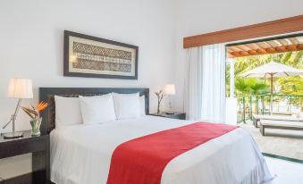 a large bed with a white and red blanket is in a room with a painting above it at Small Luxury Hotels of the World - Sublime Samana Hotel & Residences