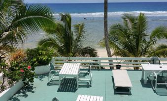 a balcony overlooking the ocean , with a table and chairs set up for outdoor dining at Paradise Inn