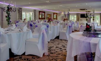 a well - decorated banquet hall with white tablecloths , chairs , and purple flowers , creating an elegant atmosphere for an event at Best Western Ivy Hill Hotel