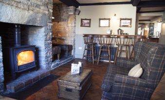 a cozy living room with a fireplace and a dining table , creating a warm and inviting atmosphere at The White Hart