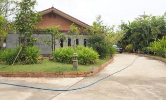 a brown house surrounded by green grass and trees , with a driveway leading up to it at Rimmueng Resort