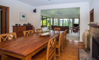 a spacious dining room with a large wooden dining table surrounded by chairs , and a kitchen visible in the background at Stay in Mudgee