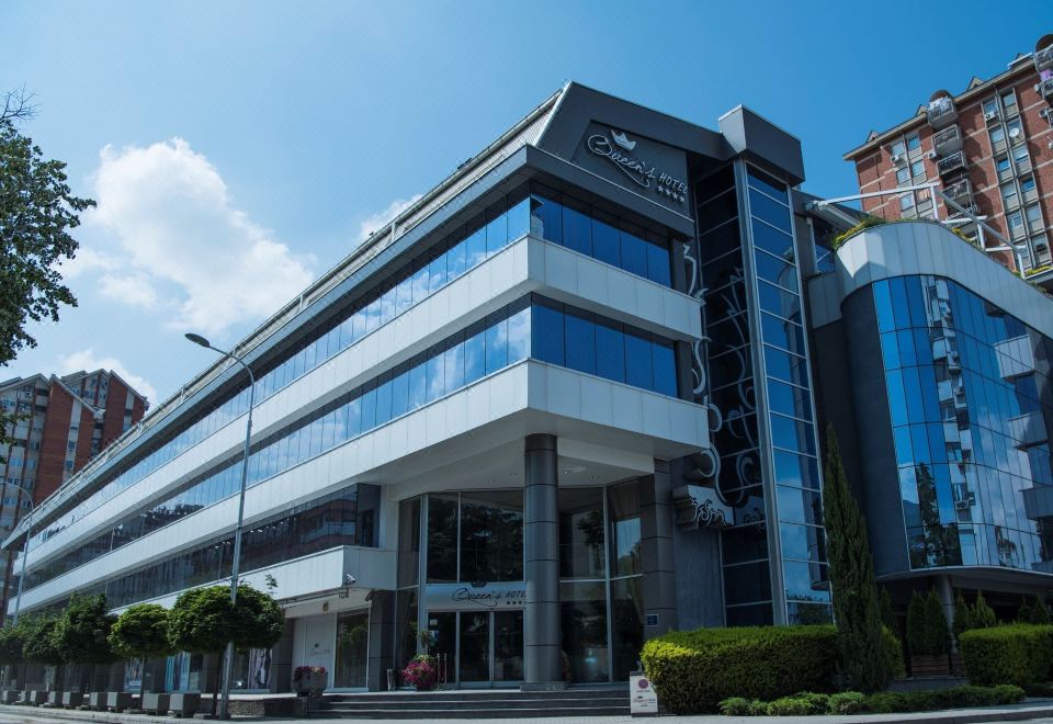 a modern office building with large windows and a black sign on the front , situated in a city at Queen's Hotel - Zebra Centre