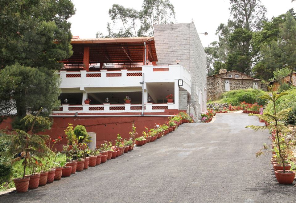 a red and white building with a balcony , surrounded by greenery and a dirt road at Park Royale