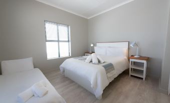 a clean and well - organized bedroom with two beds , one of which is made up with white linens and pillows at De Nada