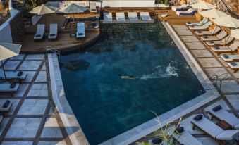a large outdoor swimming pool surrounded by lounge chairs and umbrellas , providing a relaxing atmosphere at Elounda Orama