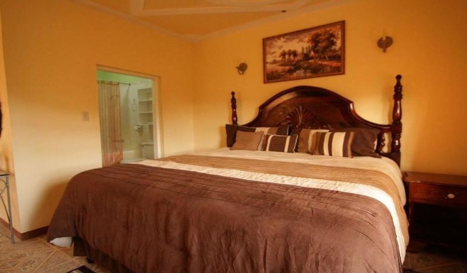 a large bed with a wooden headboard and brown bedding is in a bedroom with a window at Paradise Reggae Resort