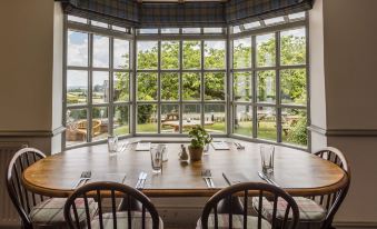 a dining room with a round table surrounded by chairs , and a large window providing natural light at The Rodney