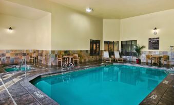 a large swimming pool is surrounded by lounge chairs and potted plants in a room at Oxford Suites Pendleton